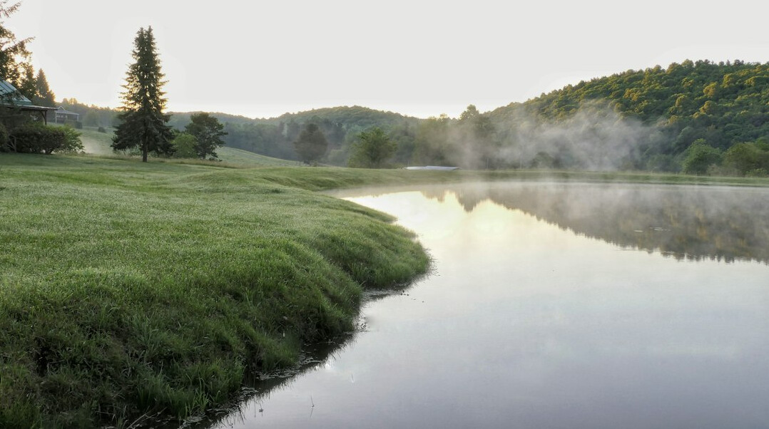 Quiet lake surrounded by hills and trees in the morning