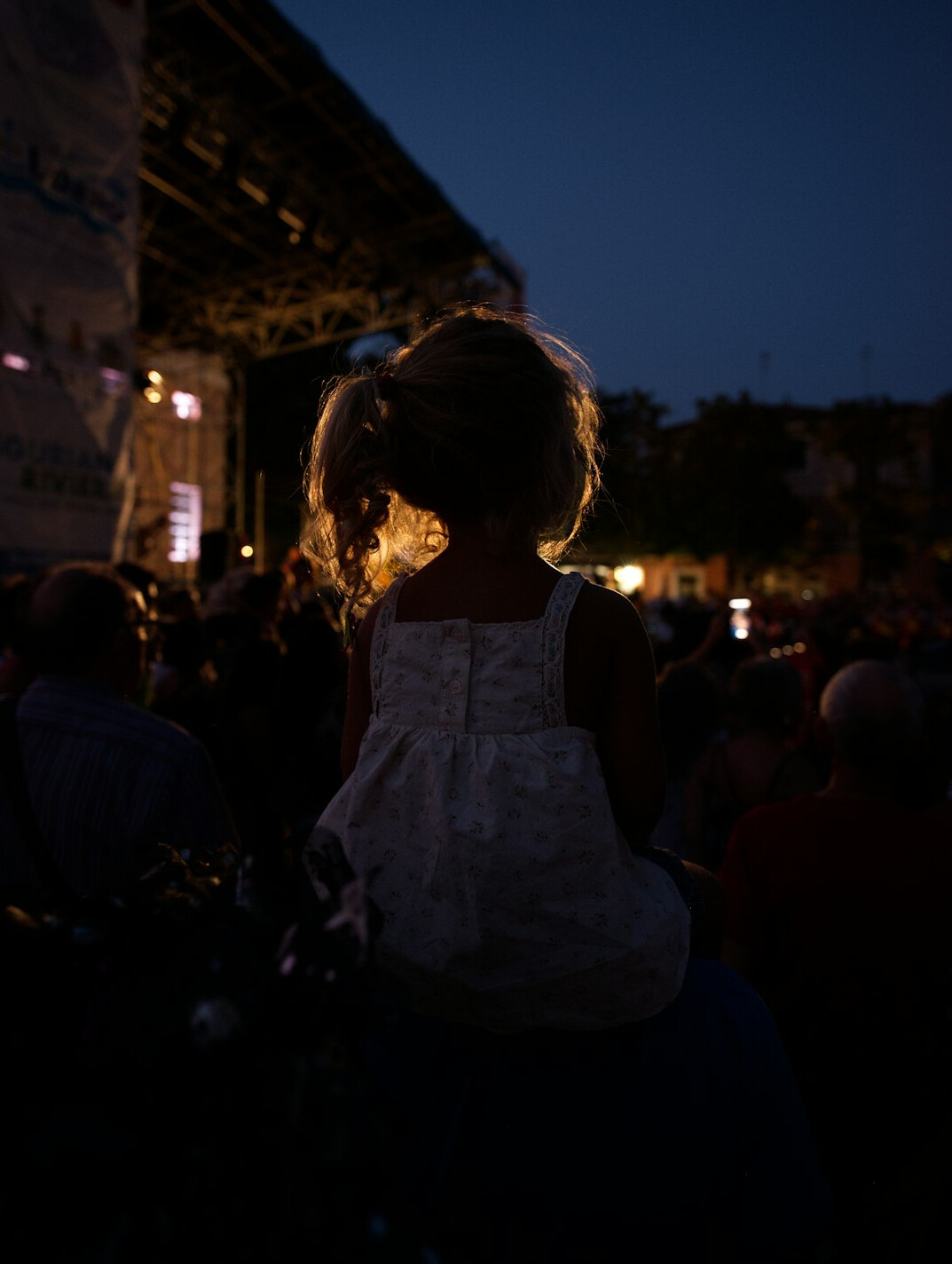 Crowd at an outdoor evening concert with stage lights